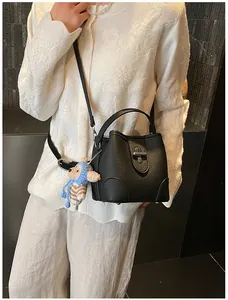 Detail of black lychee leather bucket bag with silver buckle and cute bear charm