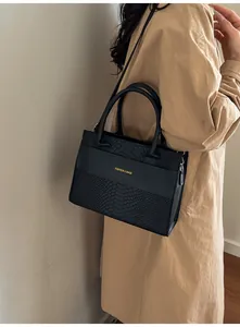 Dettaglio borsa nera in finta pelle di coccodrillo con scritta dorata elegante