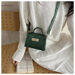 Detailed view of the dark green textured mini handbag with golden metal twist lock closure