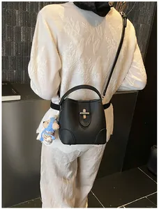 Detail of black lychee grain bucket bag with cross metal lock and cute bear charm