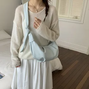 Model trägt hellblaue Halbmond-Tasche mit geknotetem Gurt im minimalistischen Stil