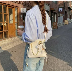Detail of cream quilted bucket bag with gold chain and leather horse charm