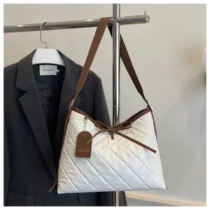 Close-up of white quilted handbag featuring a brown bow detail and FASHION tag