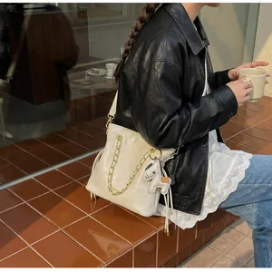 Close-up of a white quilted bucket bag with gold chain and a small horse leather charm