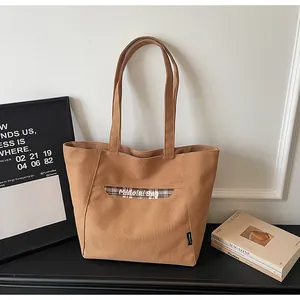Dettaglio della borsa tote in tela con tasca a quadri marroni e manici resistenti