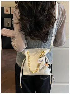 White quilted bucket bag with chain strap and horse charm worn by a model in interior