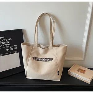 Dettaglio della borsa tote in tela beige con tasca a quadri marroni e cuciture fini