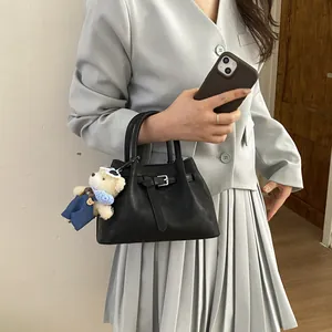 Detail view of black bucket bag with leather texture and cute white bear keychain accessory