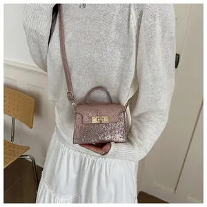 Close-up of pink metallic textured small square bag with golden rotary lock and top handle