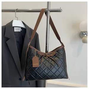 Close-up of quilted black tote bag with brown leather bow detail and fashion tag