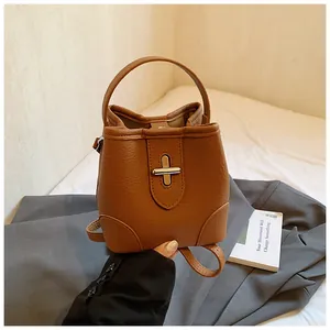 Detail of lychee textured brown bucket bag with silver cross-shaped metal lock