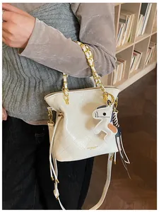 Close-up of beige quilted bucket bag with chain strap and small horse charm detail