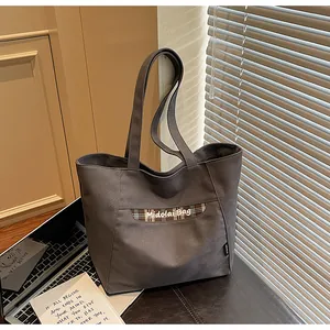Dettaglio della borsa tote in tela grigio scuro con fettuccia a scacchi marrone e testo
