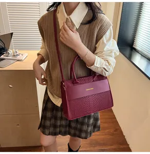 Dettaglio della trama a coccodrillo sulla borsa bordeaux con scritta Fashion & Bags