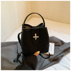 Detail of black pebbled leather bucket bag featuring silver twist lock and top handle