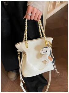 Close-up of white quilted bucket bag featuring a gold chain strap and horse charm detail