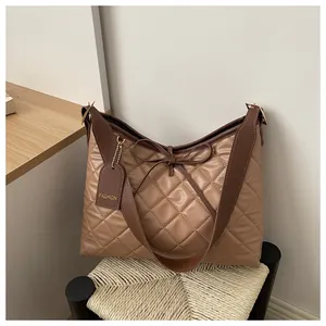 Detailed view of the checkered pattern, leather bow, and gold engraved tag on the handbag
