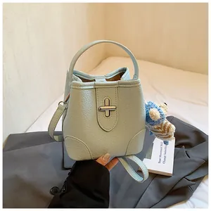 Detail of light blue pebble leather bucket bag with silver twist lock and bear charm