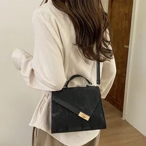 Detail of a textured black crossbody bag with gold twist lock and elegant top handle
