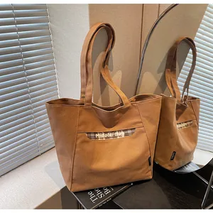 Dettaglio della borsa tote in tela con patchwork a quadri e ricamo del logo in luce soffusa