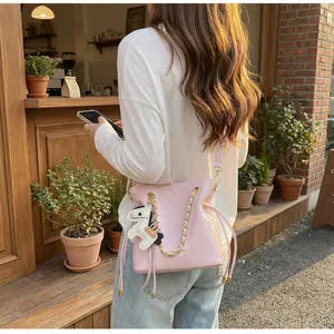 Detailed view of pink quilted bucket bag with gold chain strap and horse charm detail