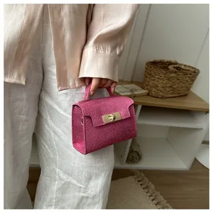 Detail of rose pink mini handbag with faux leather texture and golden twist lock closure