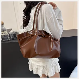 Sac seau en cuir marron poli avec boucle de ceinture porté à l'épaule pour le quotidien