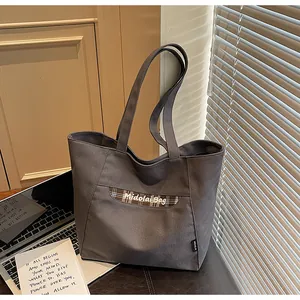 Dettaglio della borsa tote in tela grigio scuro con striscia a quadri e manici