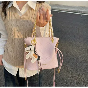 Pink quilted bucket bag with gold chain strap and cute horse charm shown on model