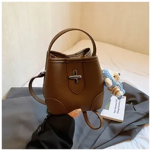 Detail view of brown pebbled leather bucket bag with silver clasp and bear charm decoration