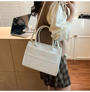 Borsa a mano bianca con motivo a coccodrillo, manici e tracolla mostrata in un set di vita