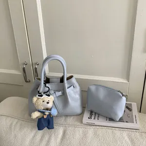Detailed view of light blue bucket bag with metal buckle and small bear charm
