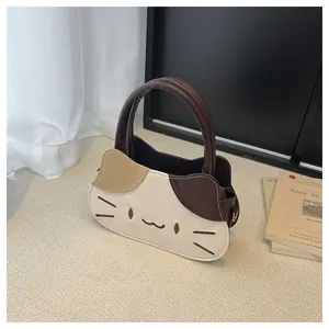 Detail of a cat-shaped handbag featuring contrast color stitching and embroidered face detail