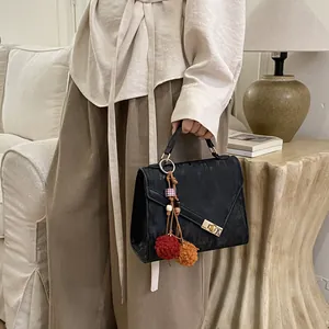 Detail of black textured handbag with colorful tassel and gold twist-lock closure