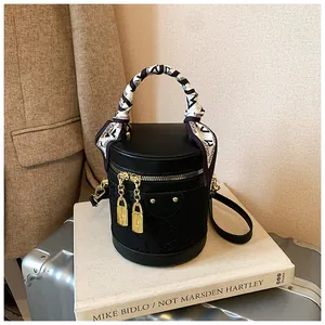 Dettaglio borsa a secchiello in pizzo nero con manico in seta e lucchetto dorato decorativo