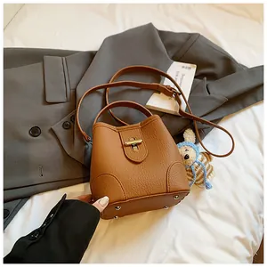 Detailed shot of brown lychee grain bucket bag with rotating metal clasp and bunny charm