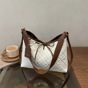 White quilted tote bag with brown leather straps and bow detail on a coffee table