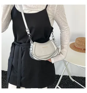 Model trägt silberne halbmondförmige Umhängetasche mit Metallic-Finish und Kettenriemen