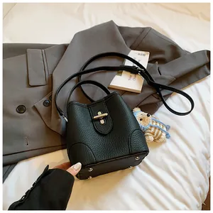 Close-up of black litchi grain leather bucket bag with silver twist lock and bear charm