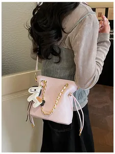 Detail of pink quilted leather bucket bag with gold chain strap and horse charm pendant