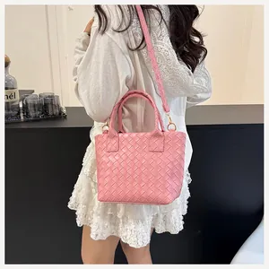 Detail view of pink woven leather tote with golden hardware on a shoulder strap