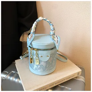 Dettaglio borsa a secchiello celeste con manico avvolto da foulard e chiusure dorate eleganti