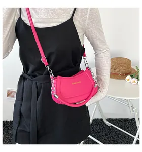 Detailansicht der pinkfarbenen Umhängetasche mit Goldlogo und silberner Kette