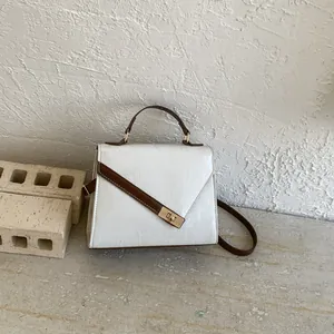 Close-up of white epi-leather texture and gold twist lock on the crossbody bag