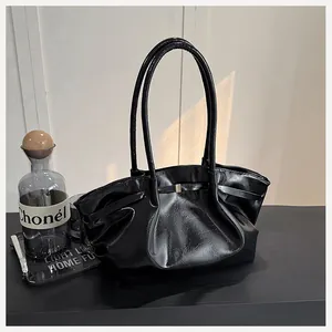 Vue détaillée du sac seau en cuir verni noir avec design plissé et boucle métallique