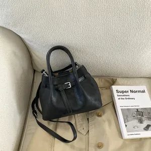 Detail view of black matte leather bucket bag with silver buckle and shoulder strap