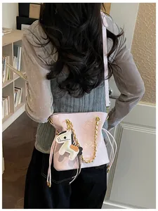 Detail of pink quilted bucket bag featuring gold chain and cartoon horse charm accessory