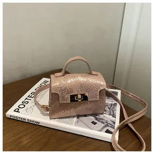 Detail of pink metallic snakeskin mini bag showing the gold twist lock and top handle