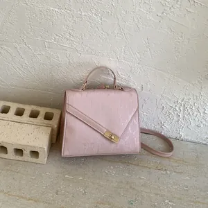 Detail of light pink crossbody bag with vertical texture and gold metal twist lock