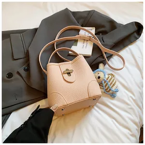 Detailed view of apricot bucket bag with lychee texture and metallic turn-lock closure